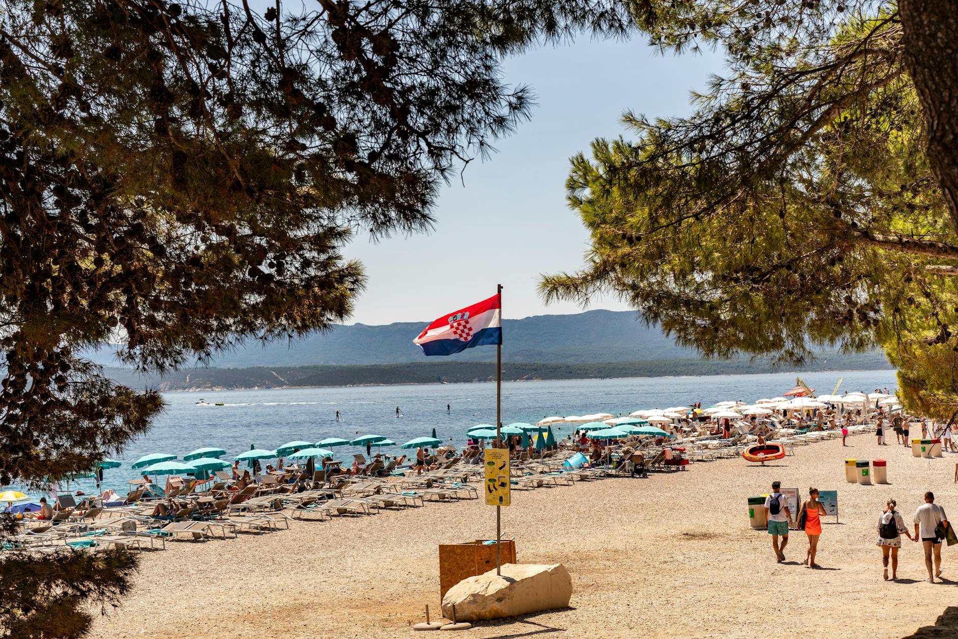 Plaża Zlatni Rat w Chorwacji latem, turyści kąpią się w turkusowym morzu