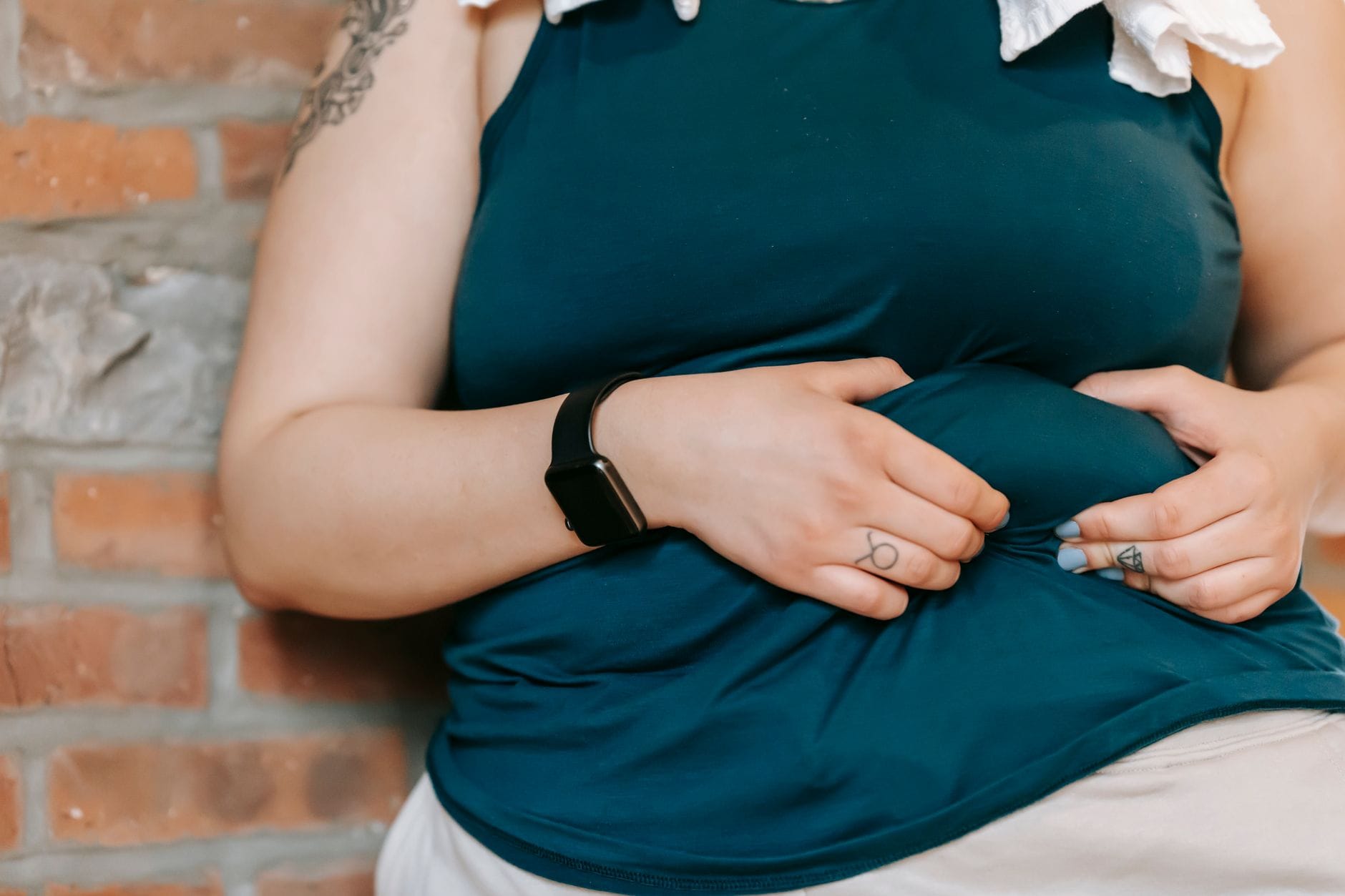 Kobieta plus size opiera się o mur i trzyma się za brzuch