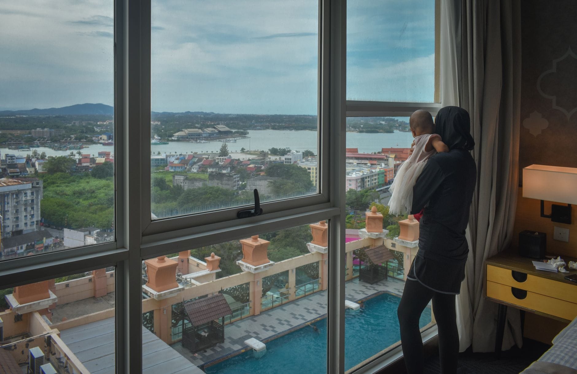 Rodzinny pobyt w Lublinie: jak wybrać hotel przyjazny dzieciom i zaplanować komfortowy weekend Mama z niemowlęciem przy oknie hotelu z widokiem na miasto i wodę