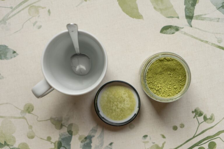 Słoik z proszkiem matcha i pusta filiżanka na kwiecistym obrusie